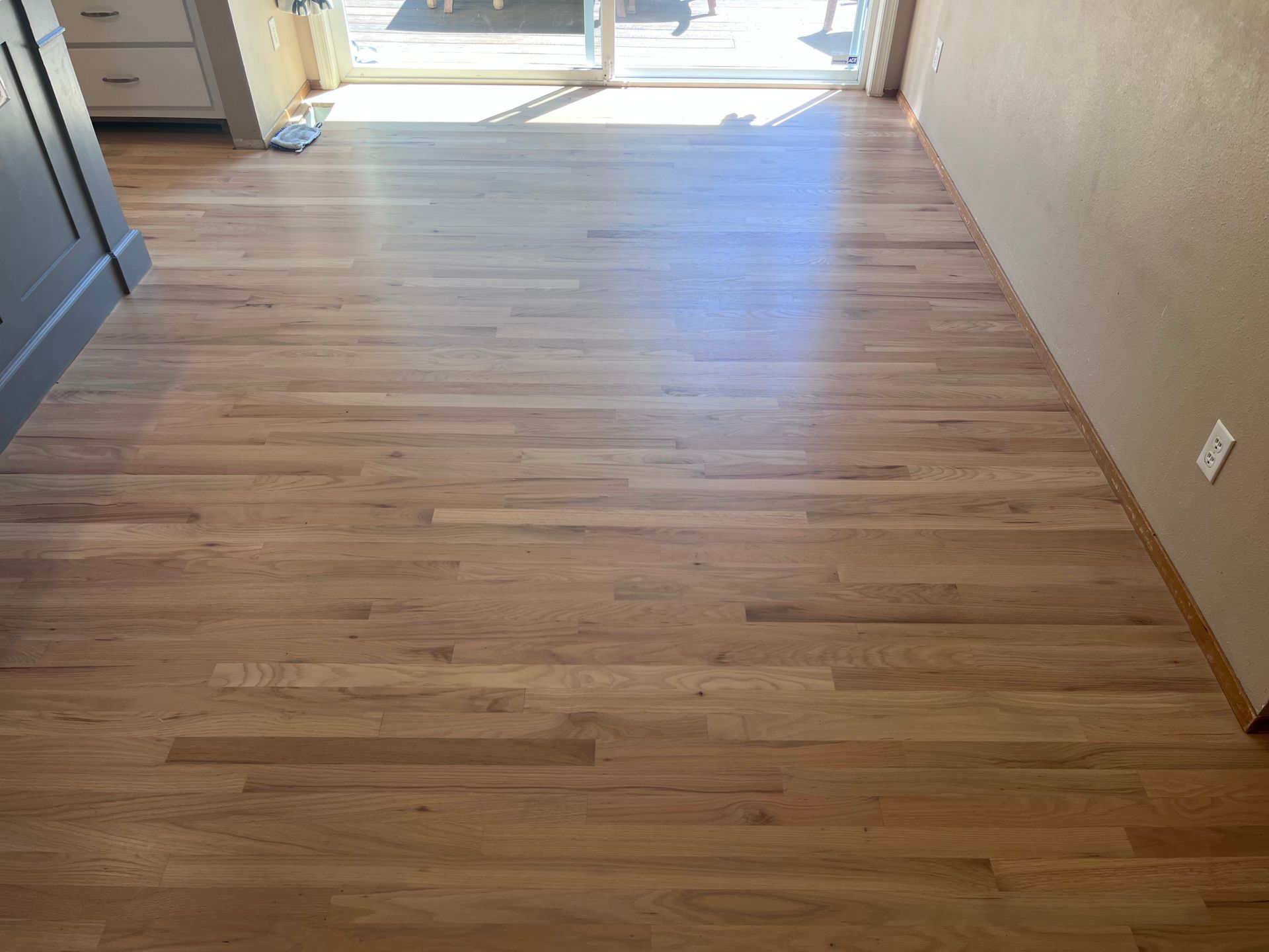 A room with a wooden floor and a sliding glass door.
