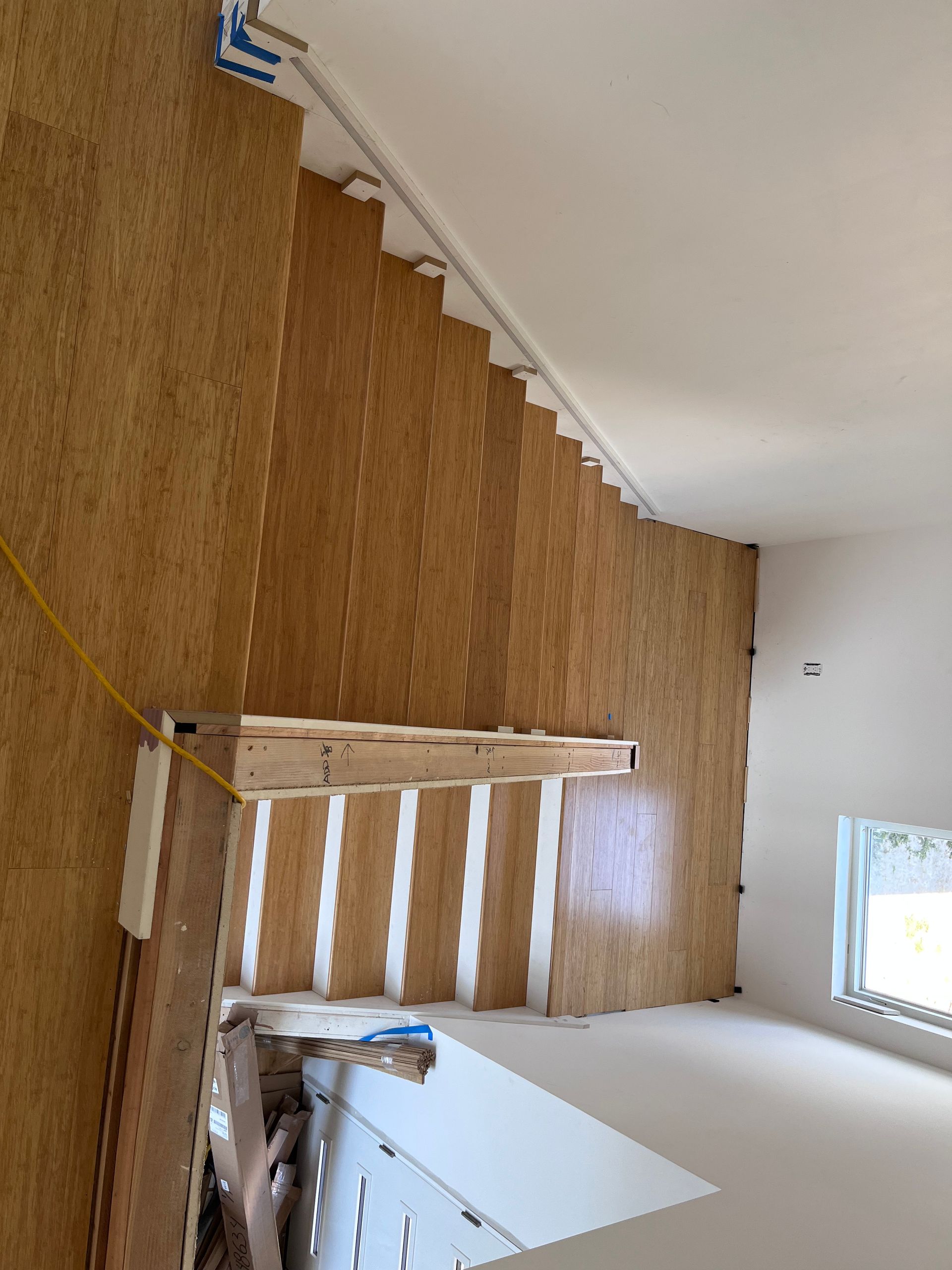 A wooden staircase is being built in a room with a window.