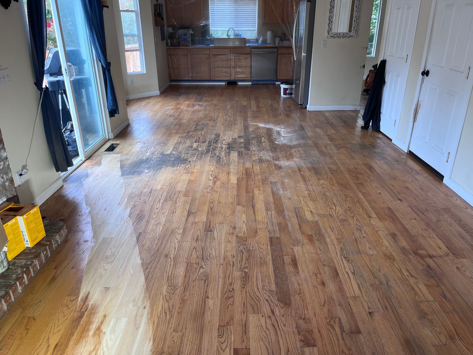 A living room with hardwood floors and a kitchen in the background.
