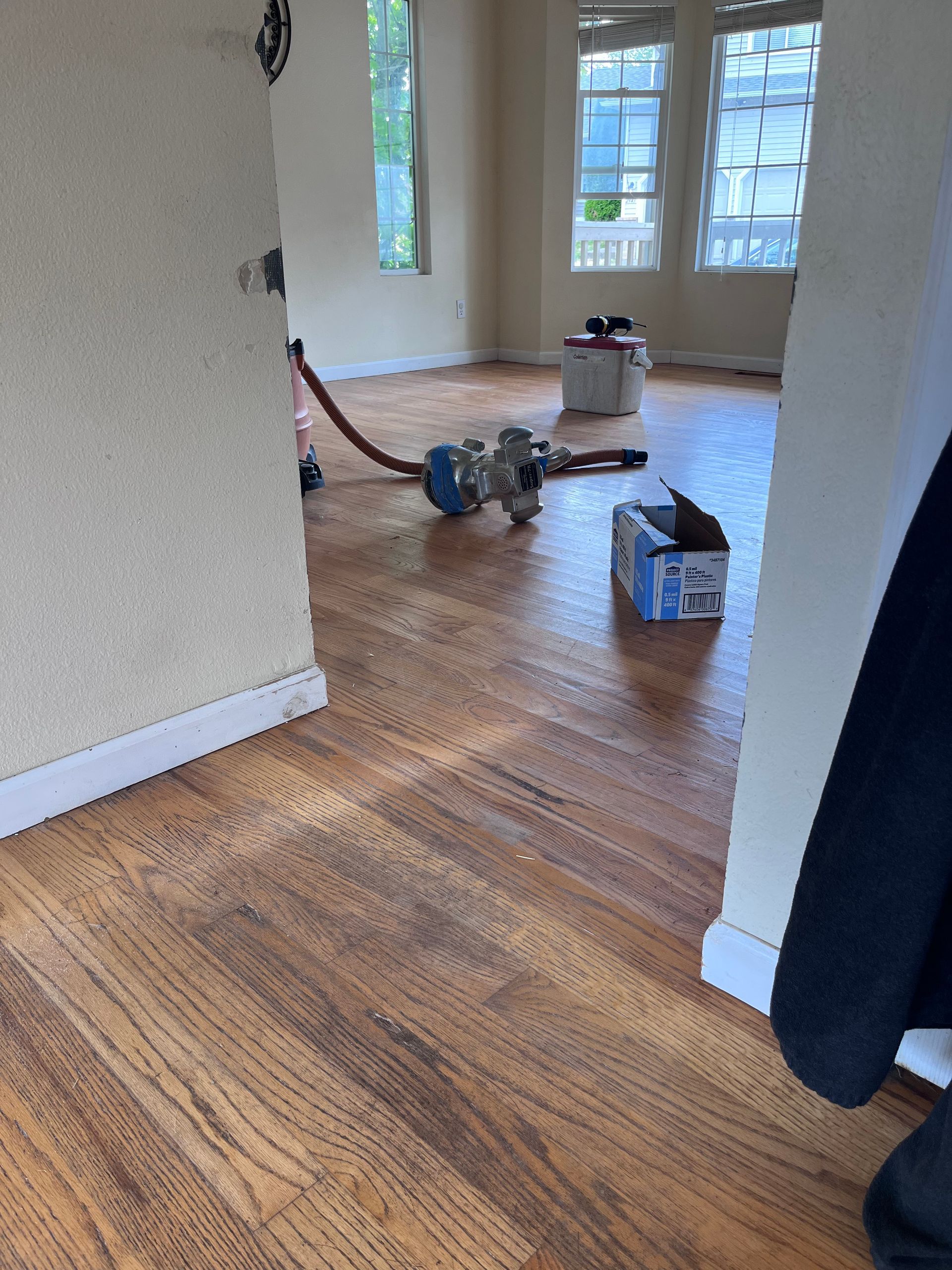 A vacuum cleaner is sitting on a wooden floor in an empty room.