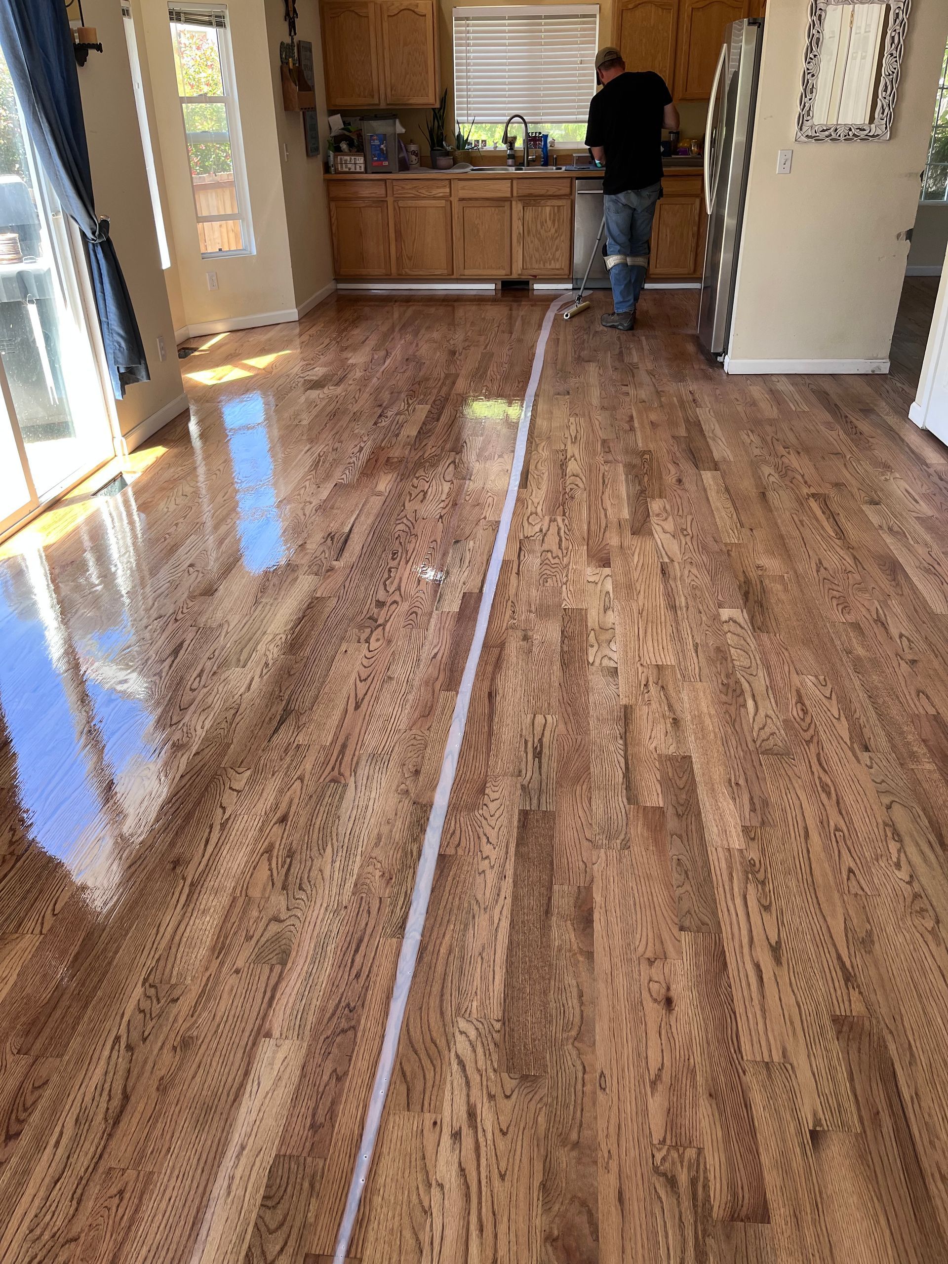A man is standing on a wooden floor in a kitchen.