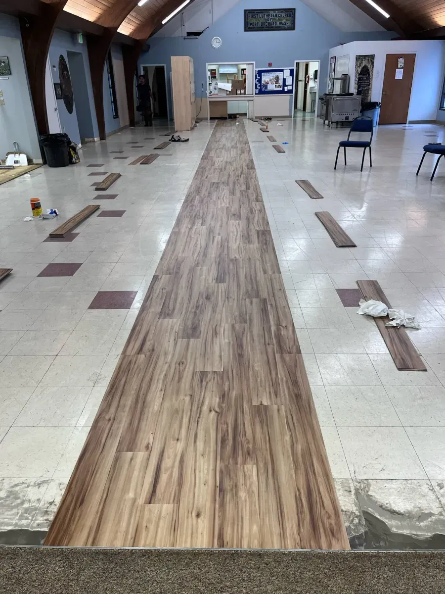 A long hallway with wooden flooring being installed in a church.