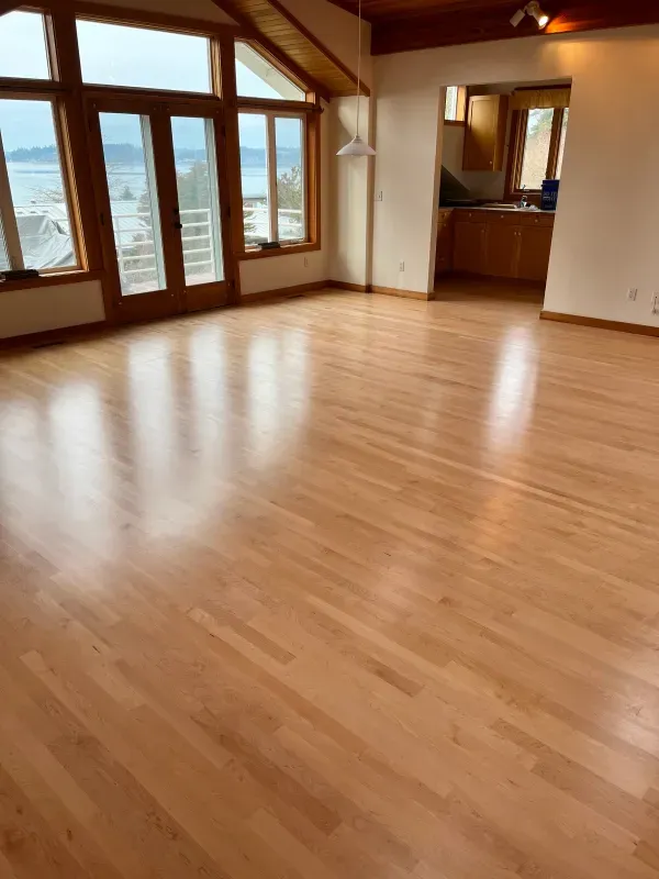 An empty living room with hardwood floors and lots of windows