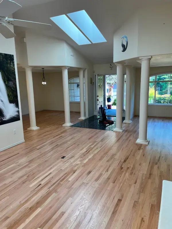 A large empty room with hardwood floors and columns