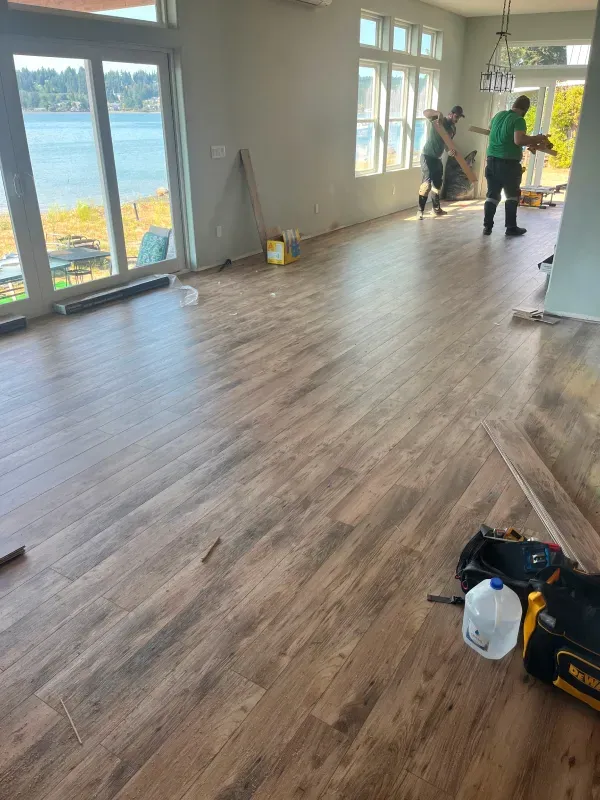 A group of people are working on a wooden floor in a living room.