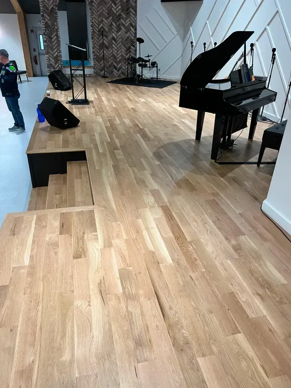 A piano is sitting on a wooden floor in a room.