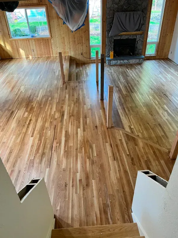 A living room with hardwood floors and stairs and a fireplace.