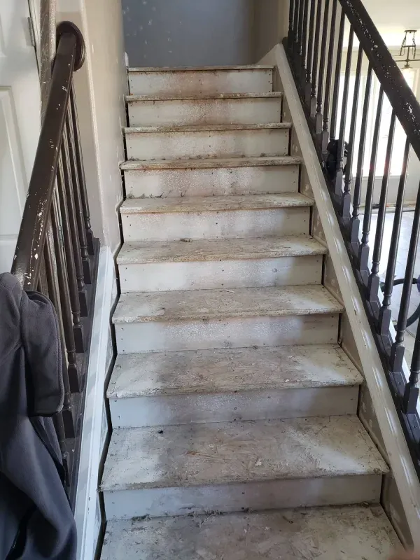 A person is standing next to a set of stairs in a house.
