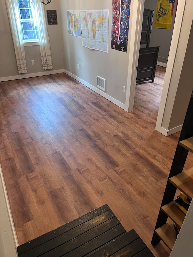 A wooden floor in a hallway leading to a living room.