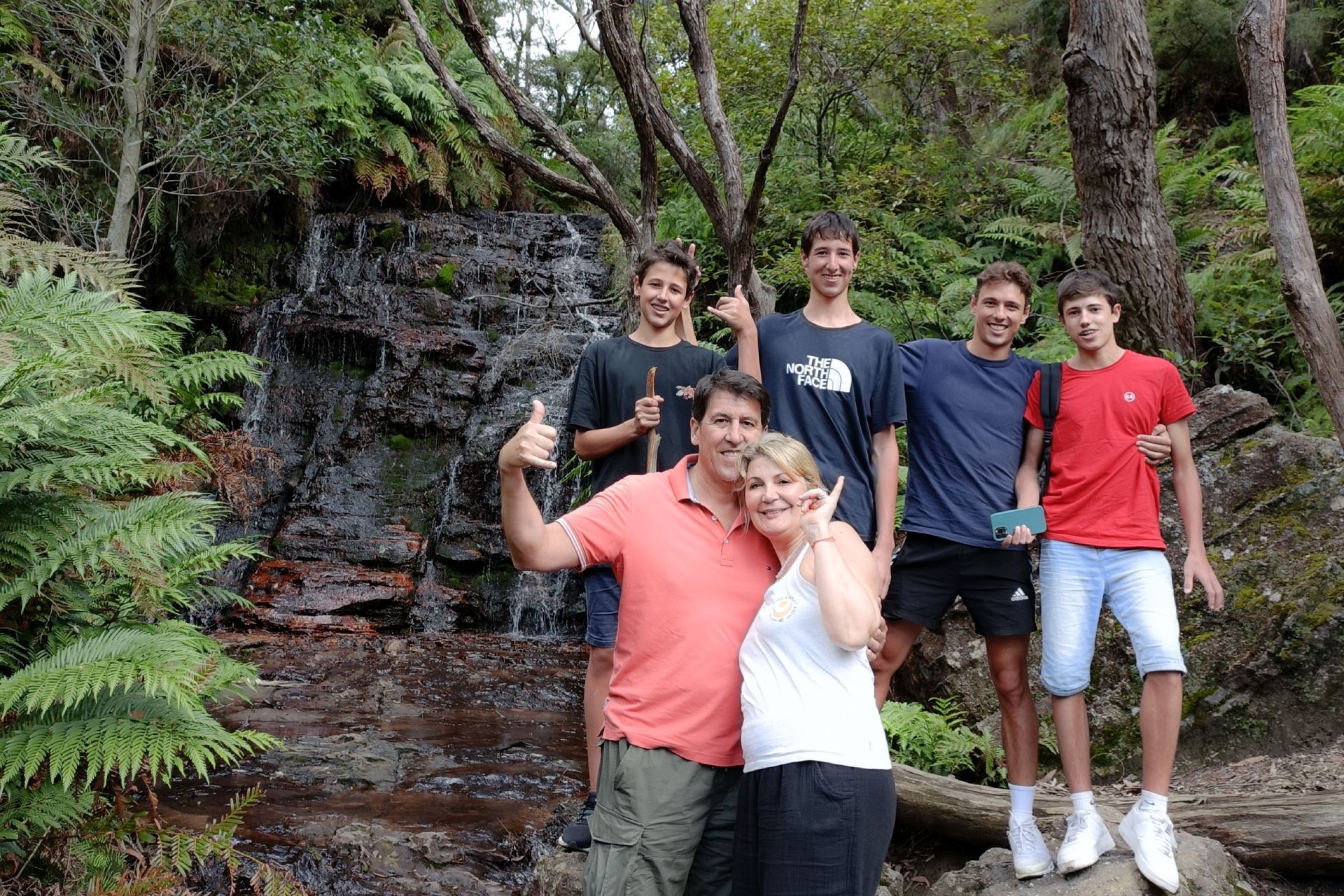 A group of people are posing for a picture in front of a waterfall.