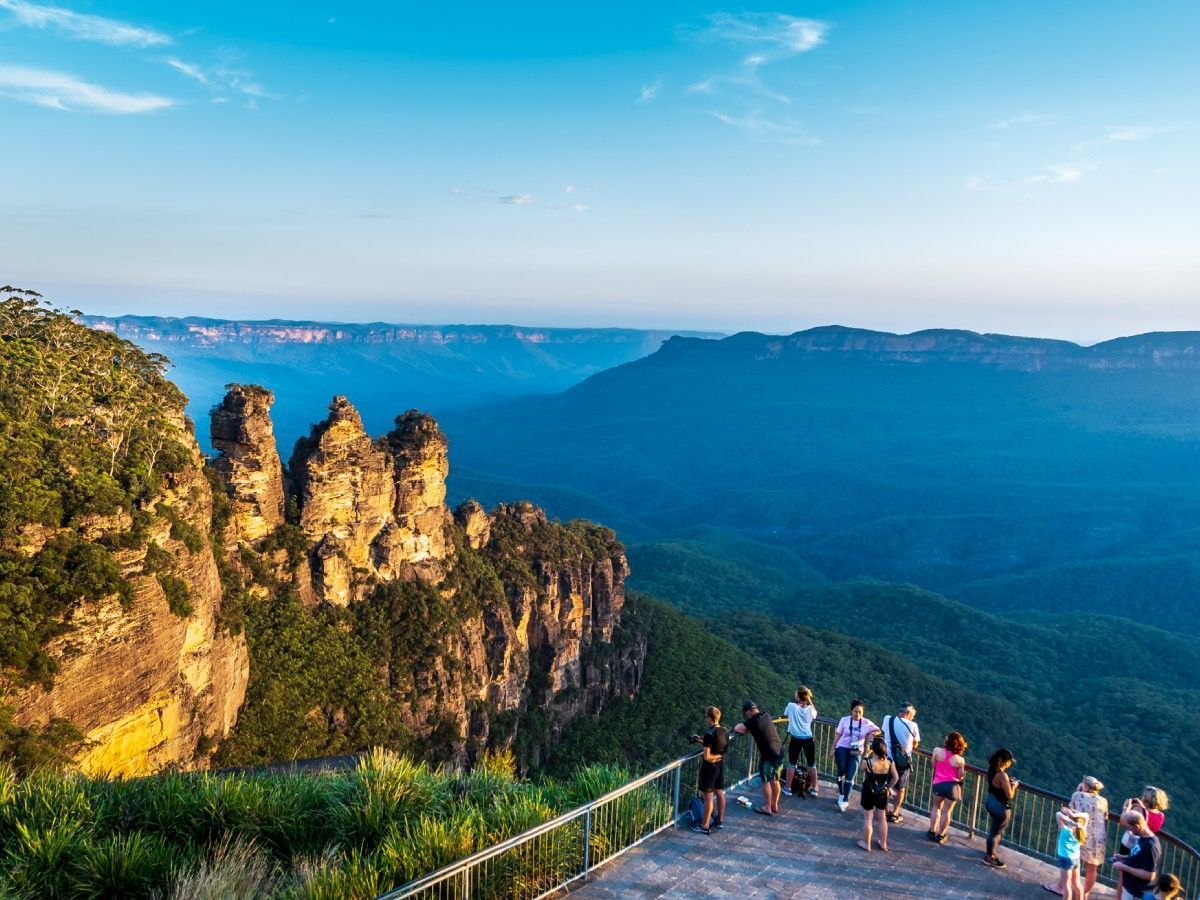 A group of people are standing on top of a cliff overlooking a valley.