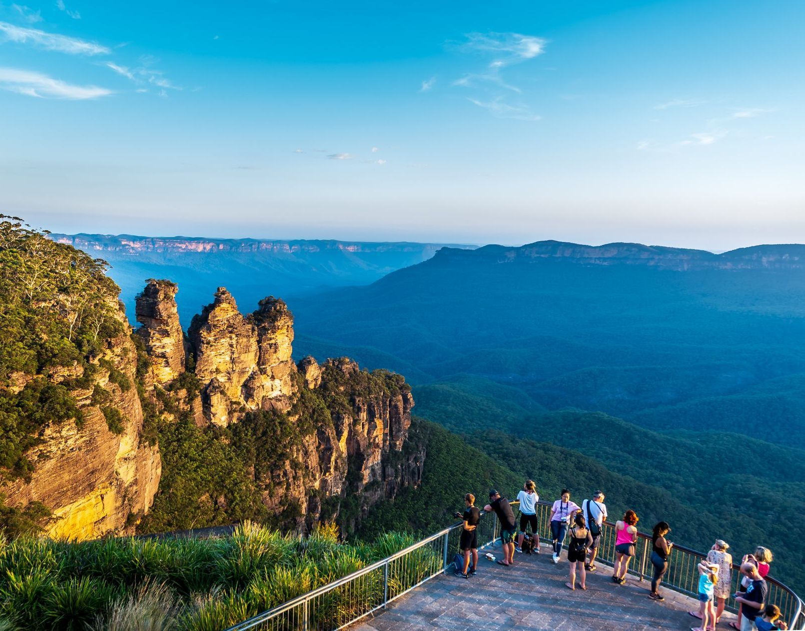 A group of people are standing on top of a cliff overlooking a valley.
