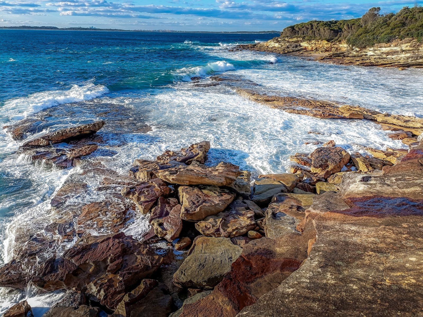 The waves are crashing against the rocks on the shore of the ocean.