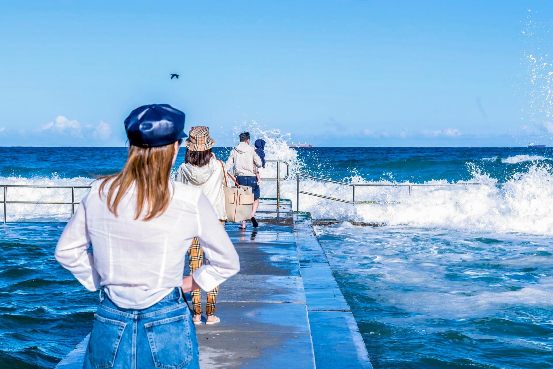 A woman is standing on a pier overlooking the ocean.