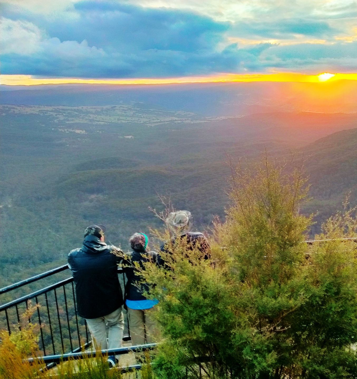 Two people looking at the sunset over a valley
