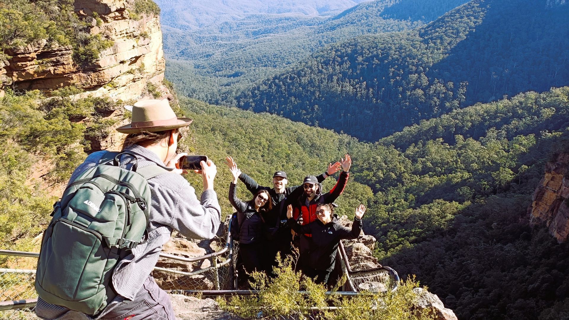 A man is taking a picture of a group of people on top of a mountain.