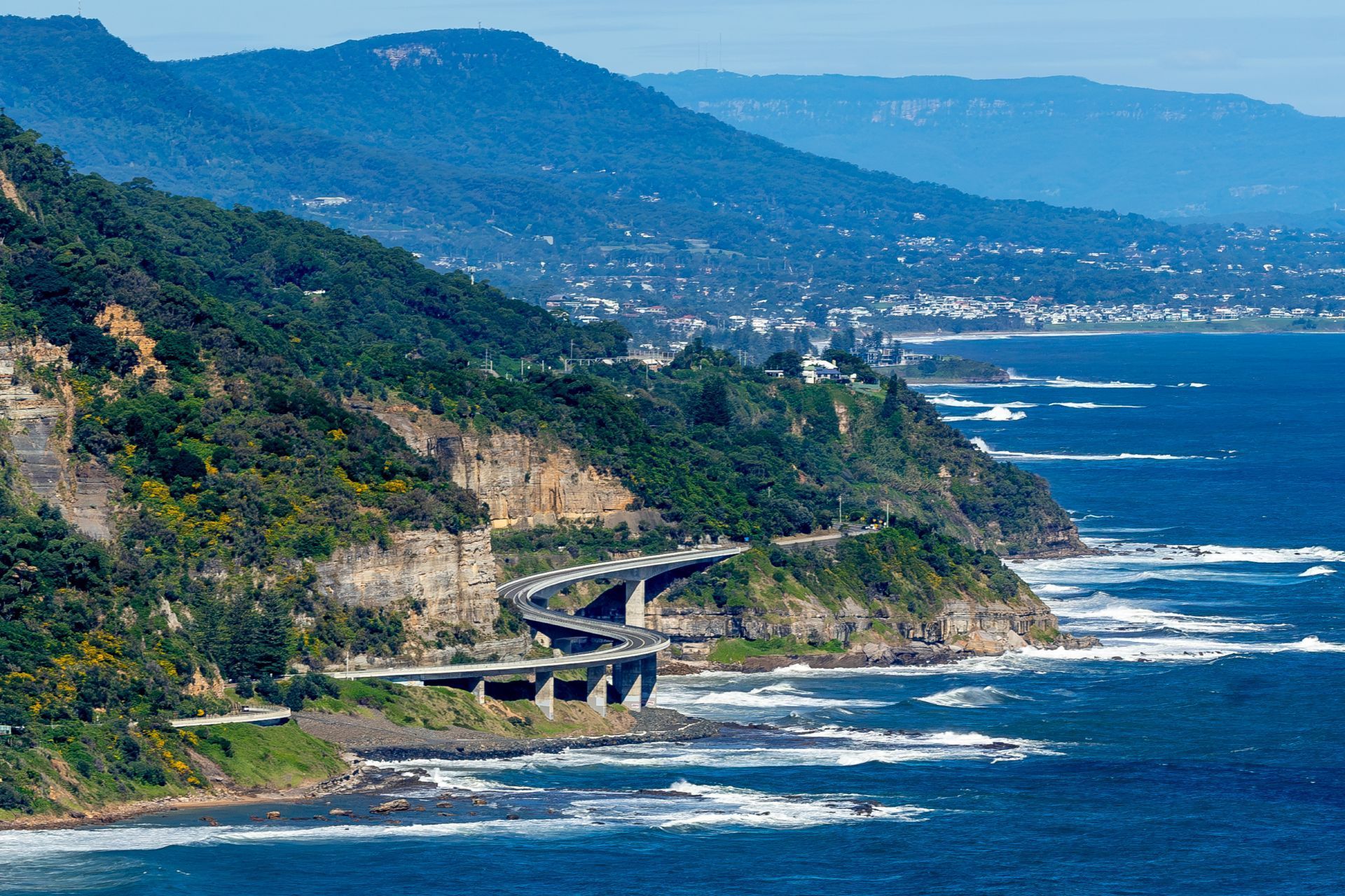 A view of a cliff overlooking the ocean with mountains in the background