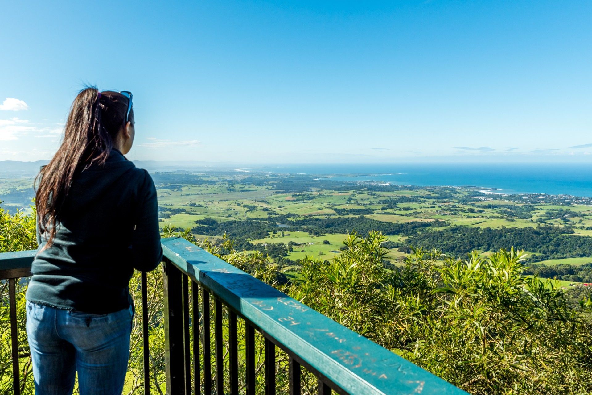 A woman is standing on a balcony overlooking a lush green valley.