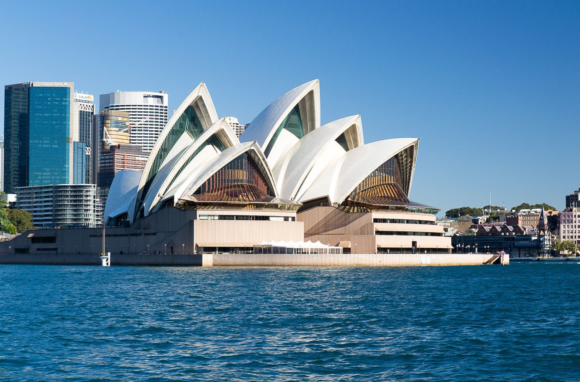 The sydney opera house sits in the middle of a body of water