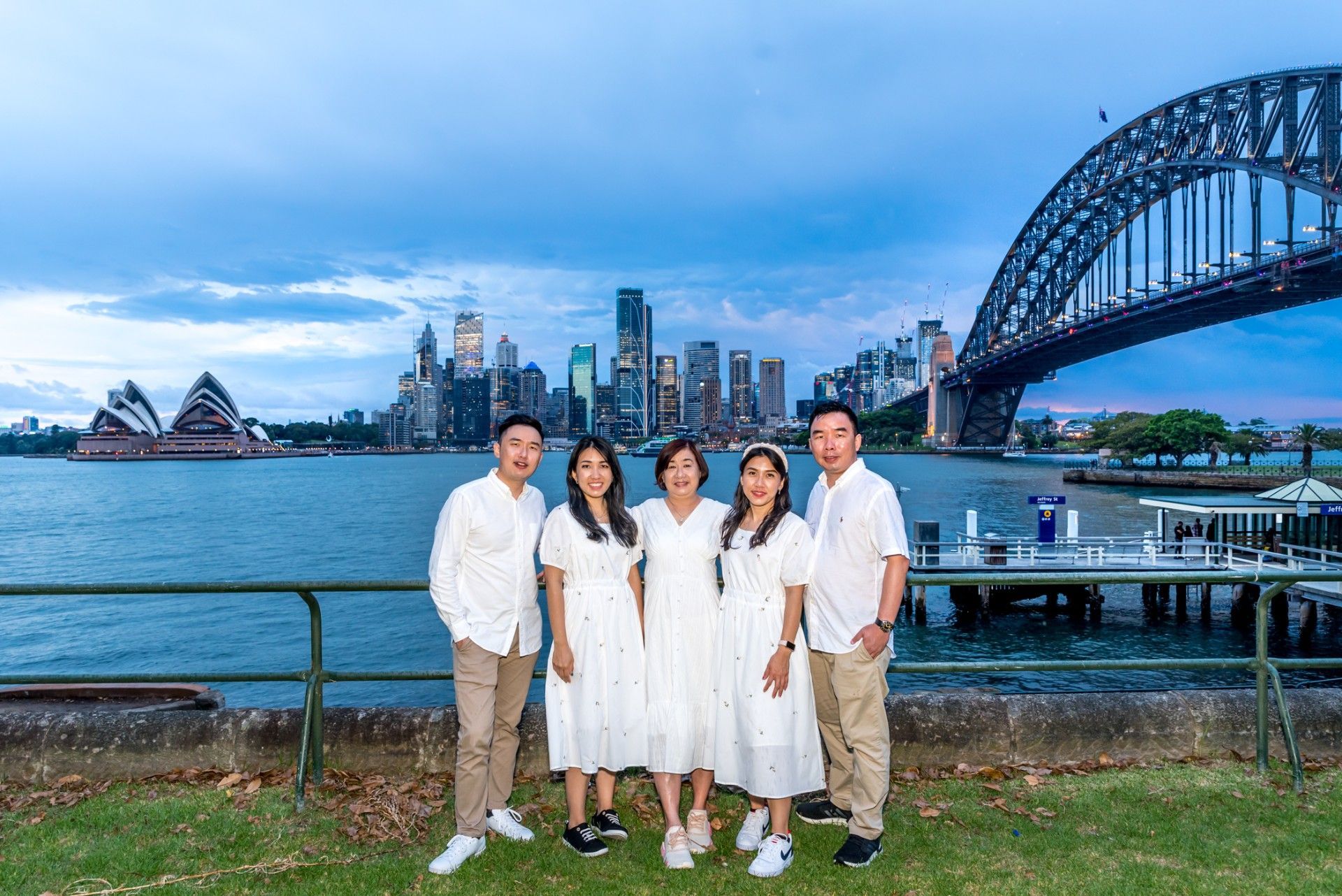A group of people are posing for a picture in front of a harbor with a bridge in the background.