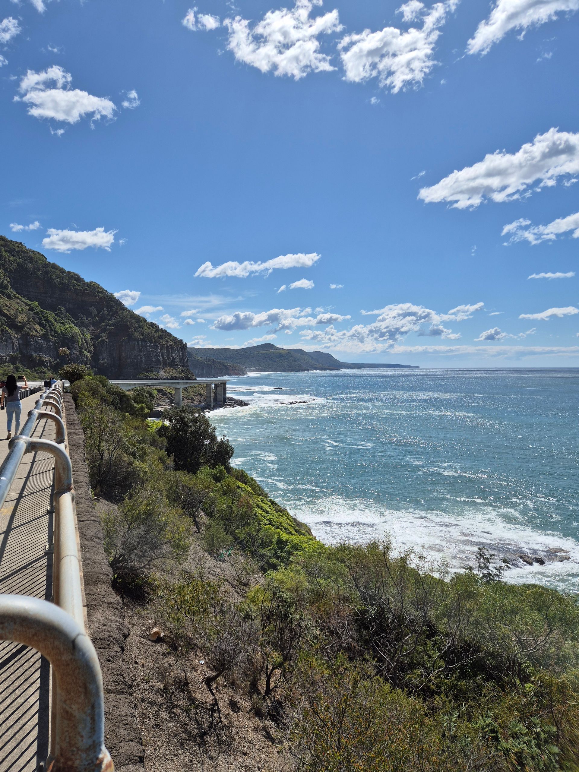 A person holding a camera looks over the valley at sunset