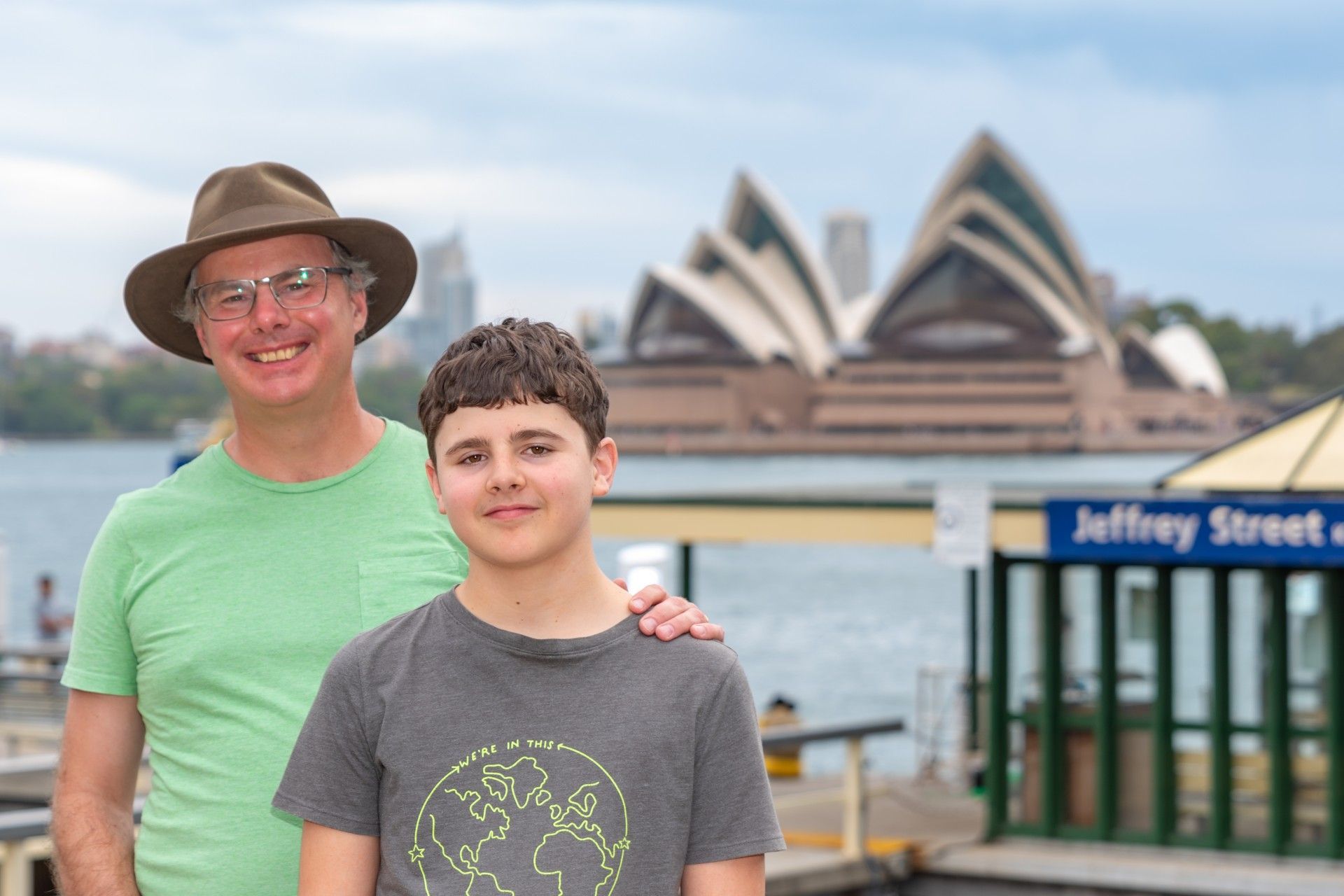Father and son are posing for a picture in front of the opera house