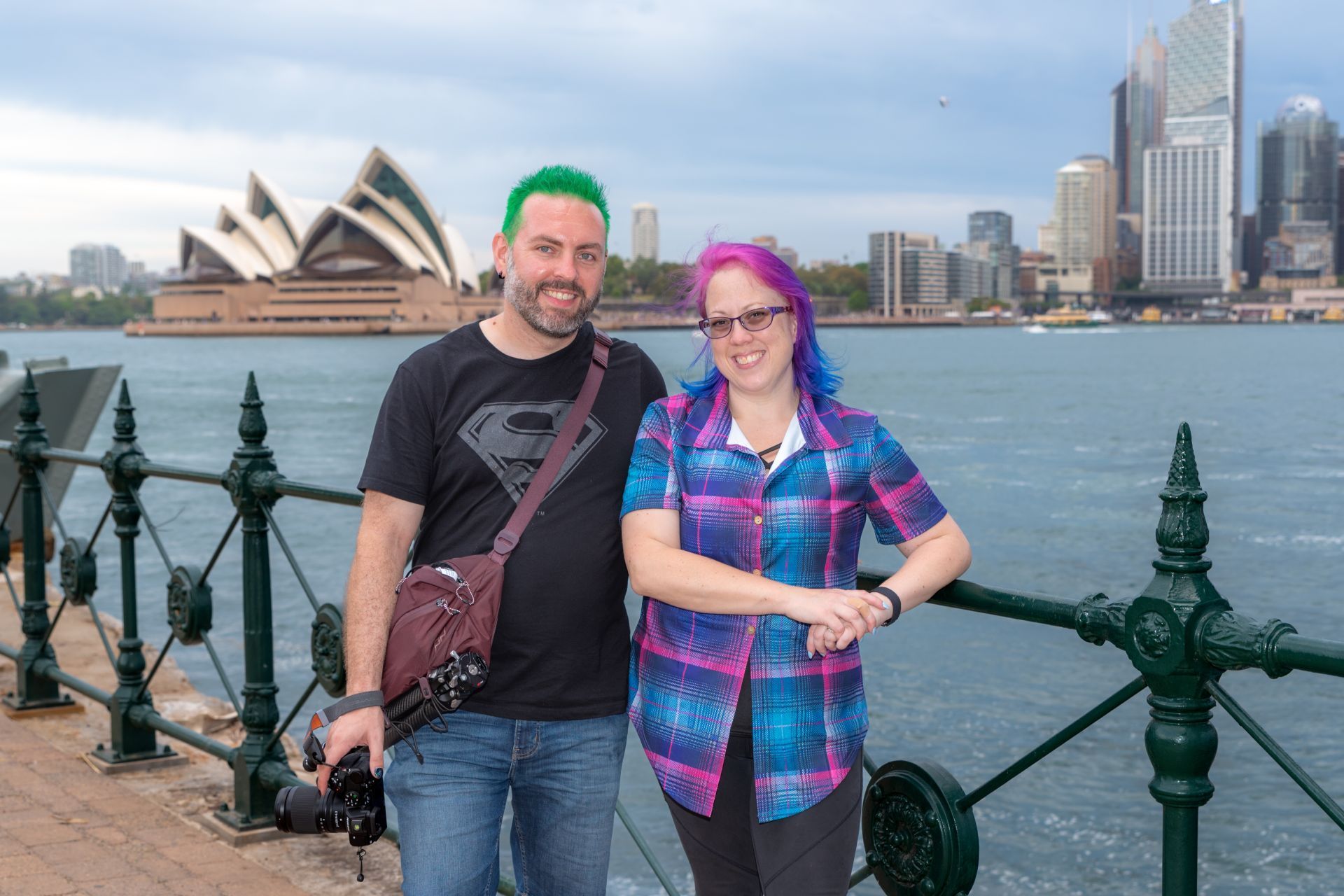 A man and a woman are posing for a picture in front of the opera house in Sydney