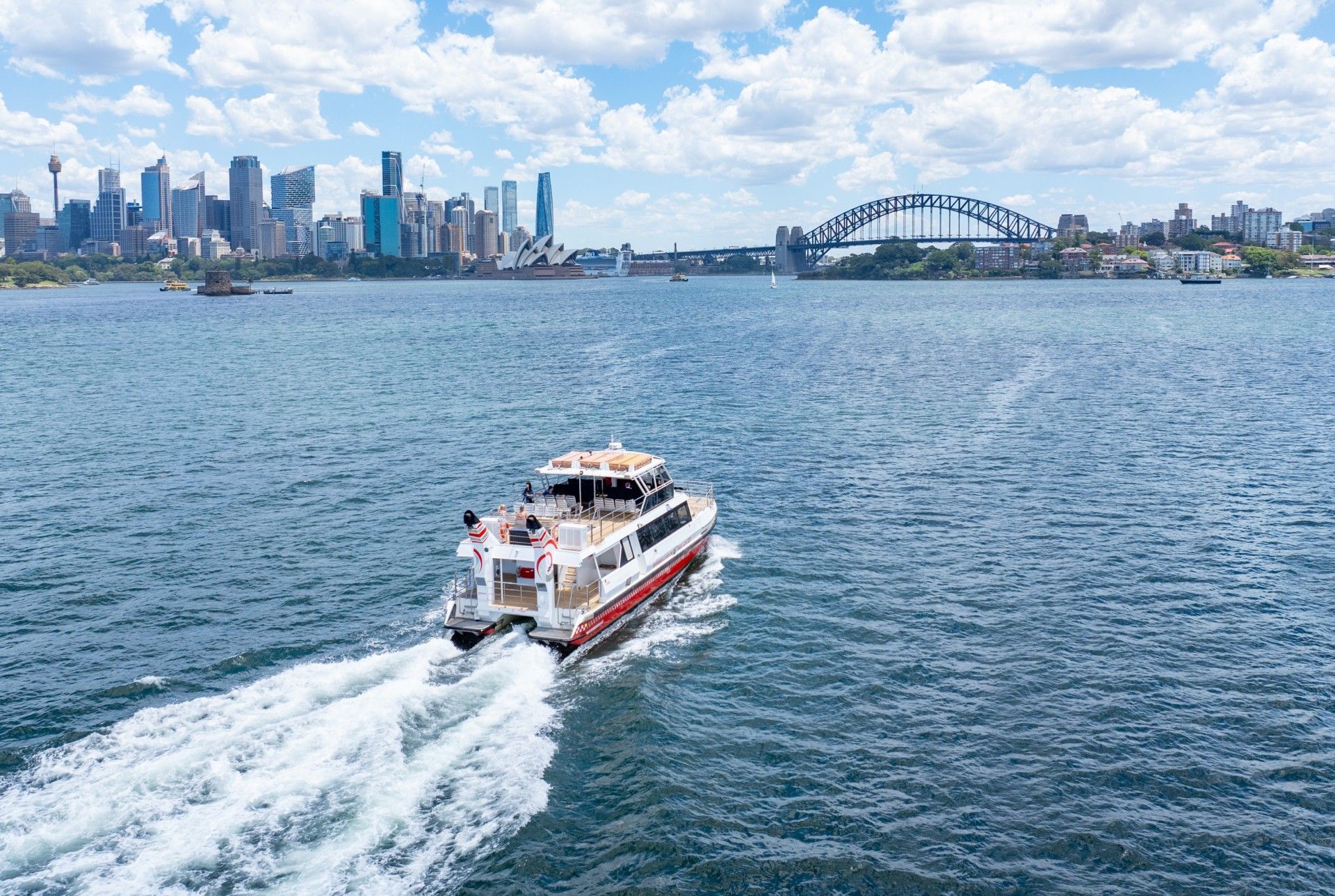 A boat is floating on top of a body of water with a city skyline in the background.
