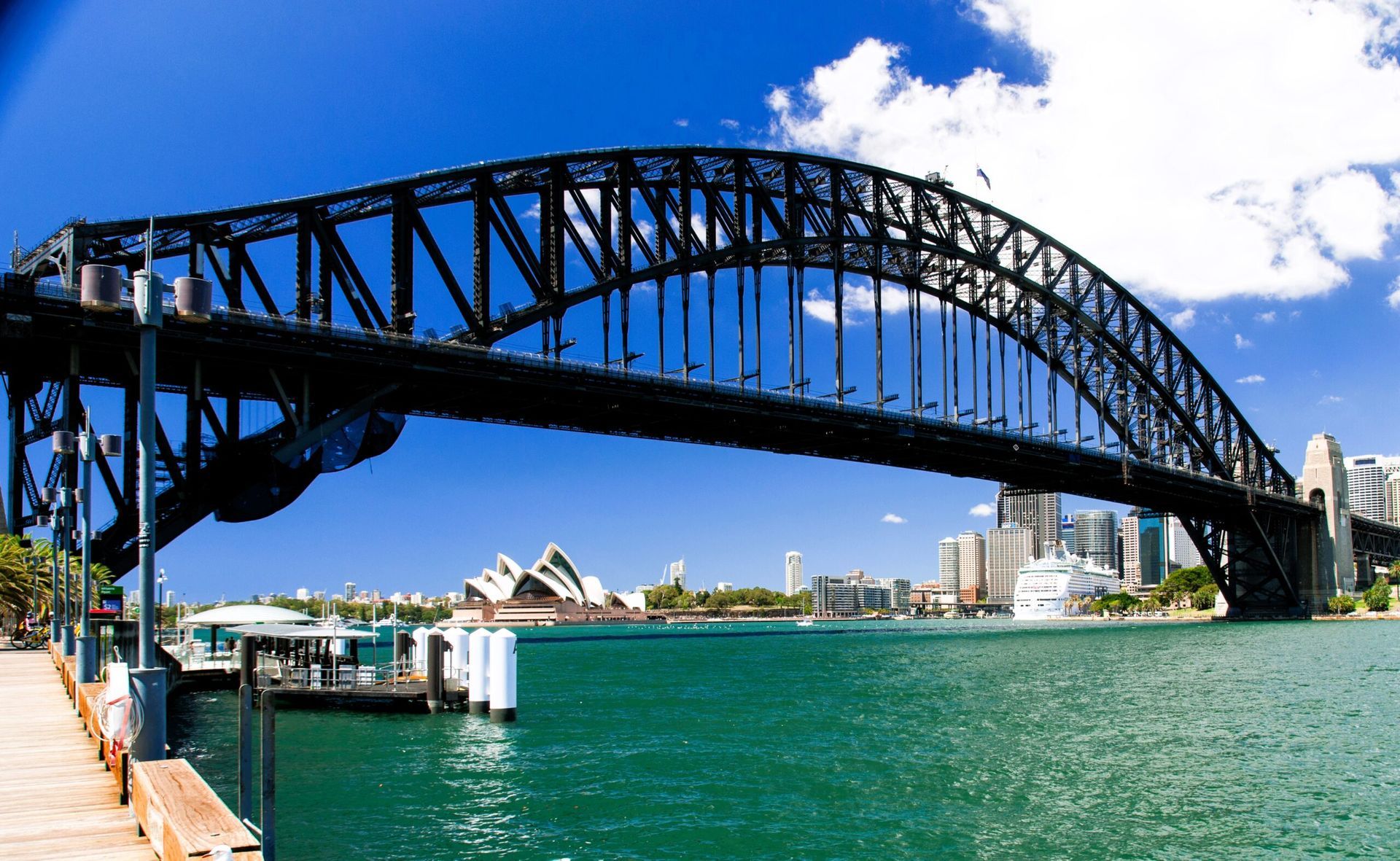 A bridge over a body of water with the opera house in the background