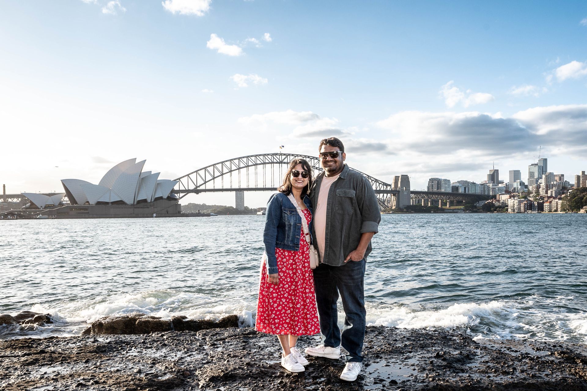 A man and a woman are posing for a picture in front of a body of water.