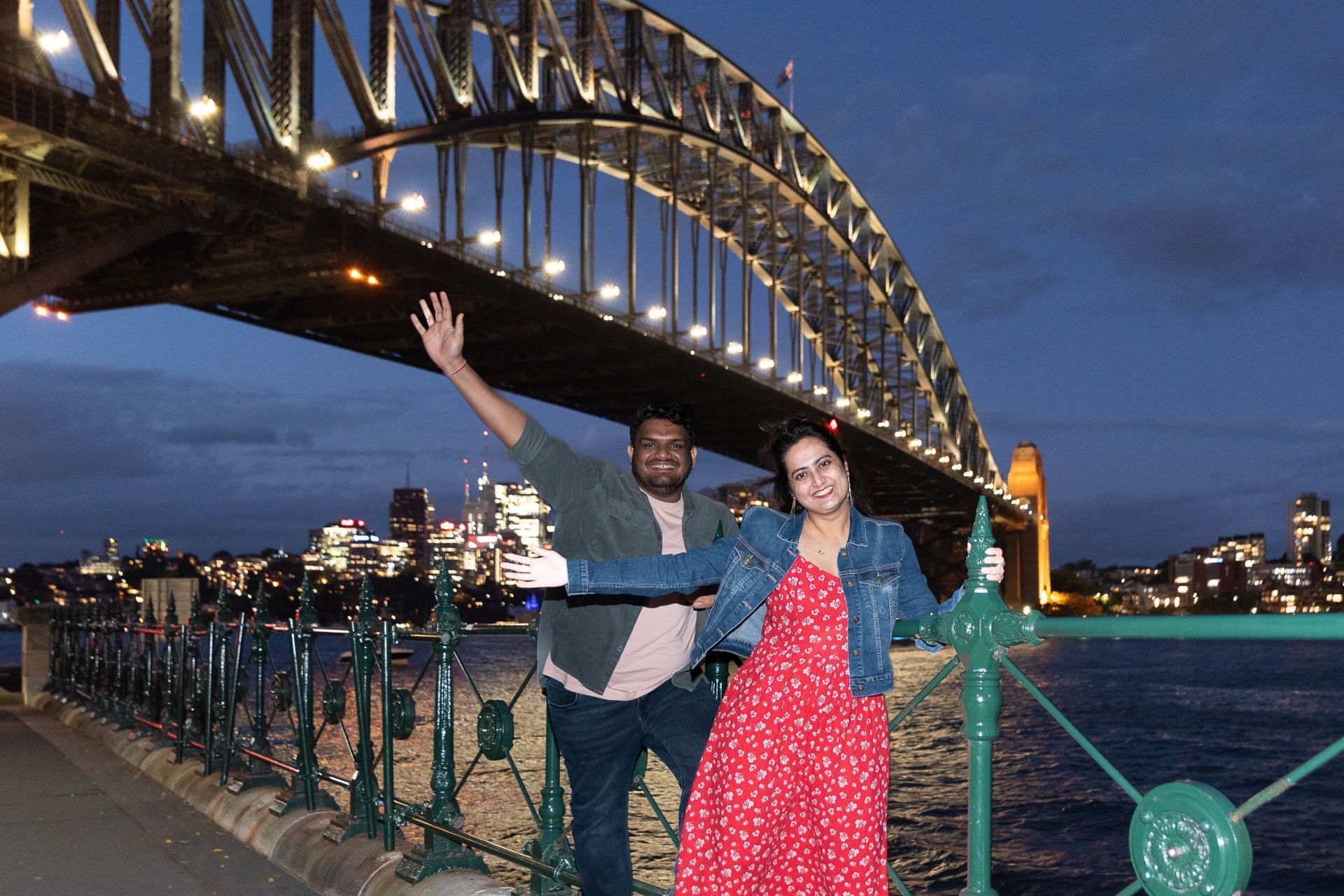 A man and a woman are posing for a picture in front of a bridge