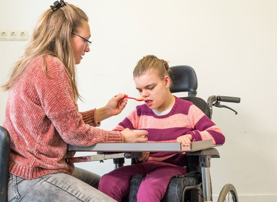 A Disabled Child In A Wheelchair Together With Care Worker  — iCan Support Services Kawana QLD