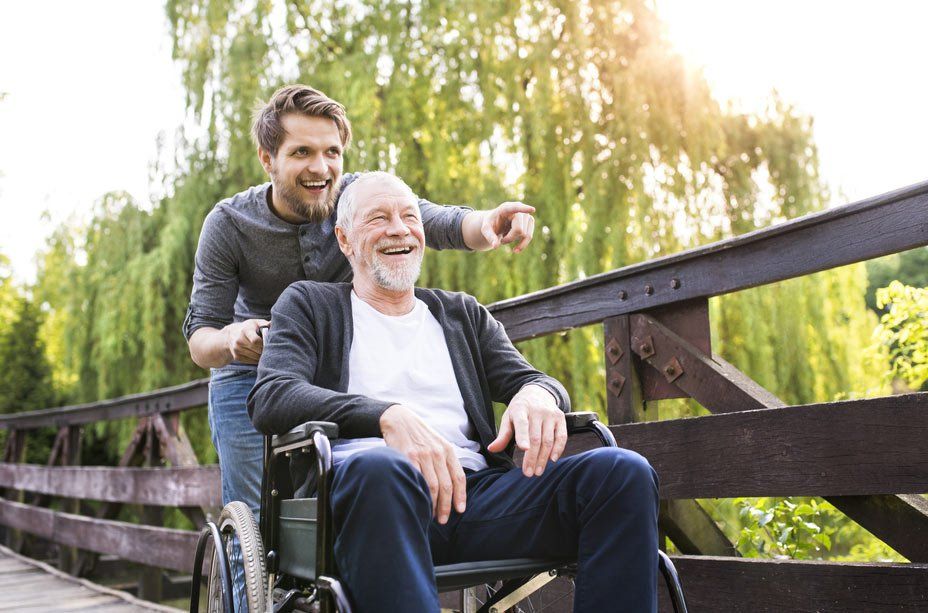 Men Care Worker With Disabled Person Are Smiling On The Park — iCan Support Services Kawana QLD