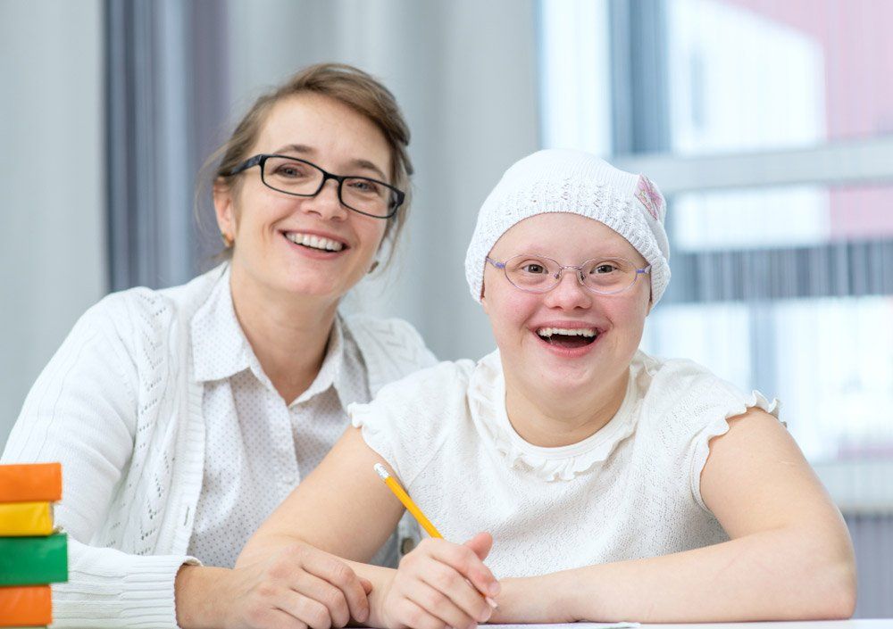 Portrait Of Happy Care Worker And Girl With Down Syndrome At Home — iCan Support Services Kawana QLD