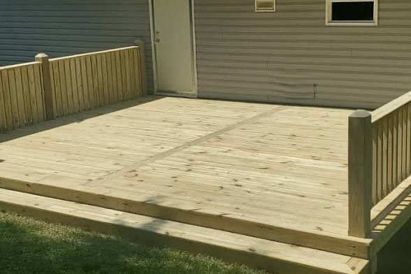 Wooden deck with railing, steps, and door against a gray house.