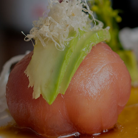 A close up of a sashimi with a green leaf on top