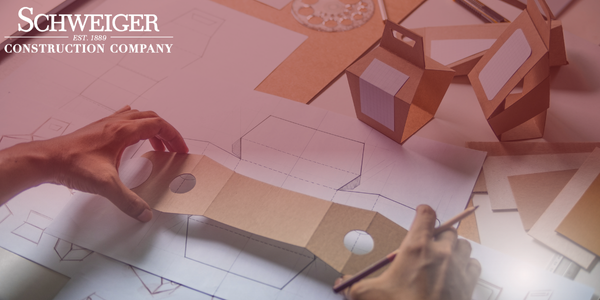 A person is working on a blueprint for a schweiger construction company
