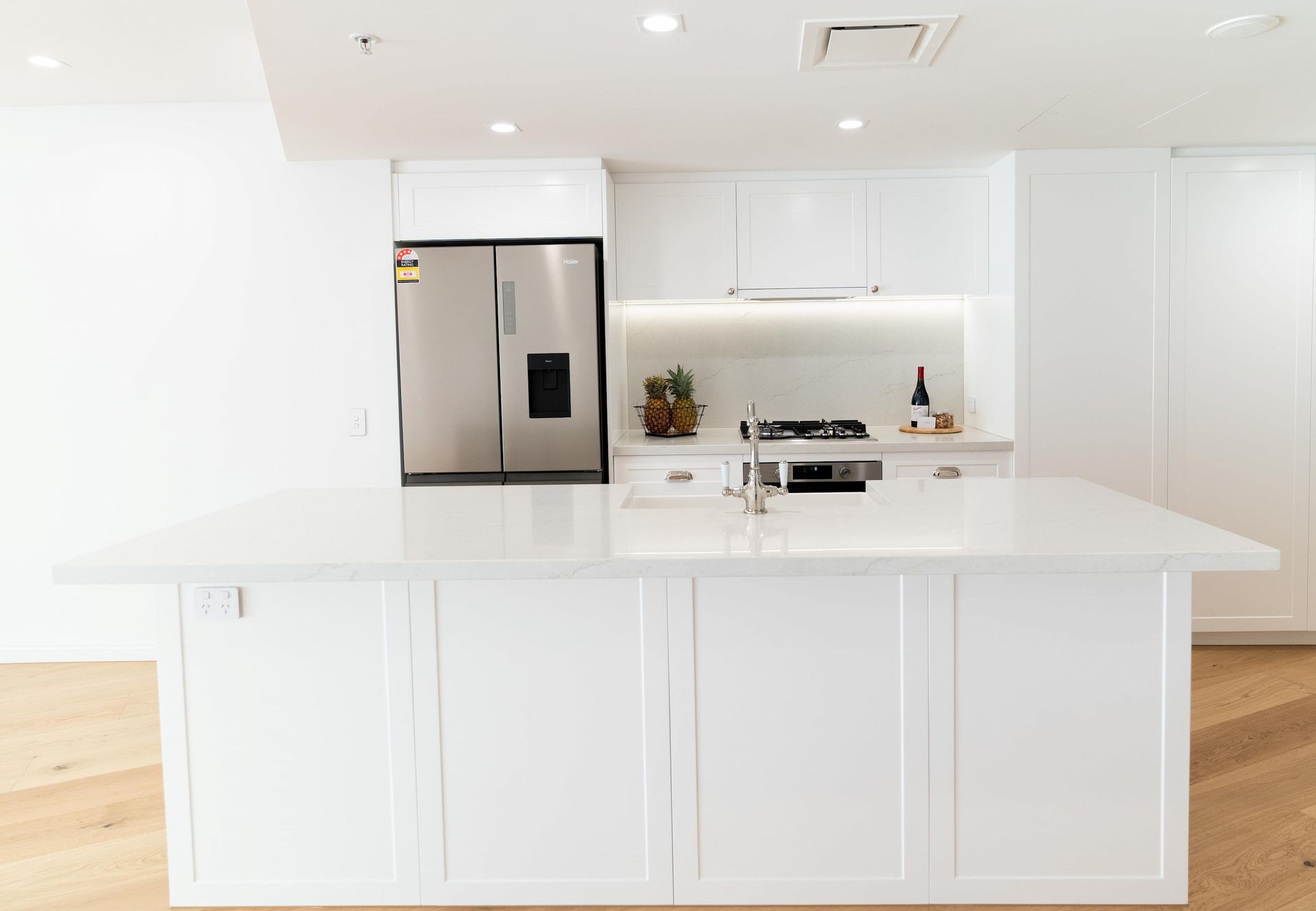 A kitchen with white cabinets , stainless steel appliances , and a large island.