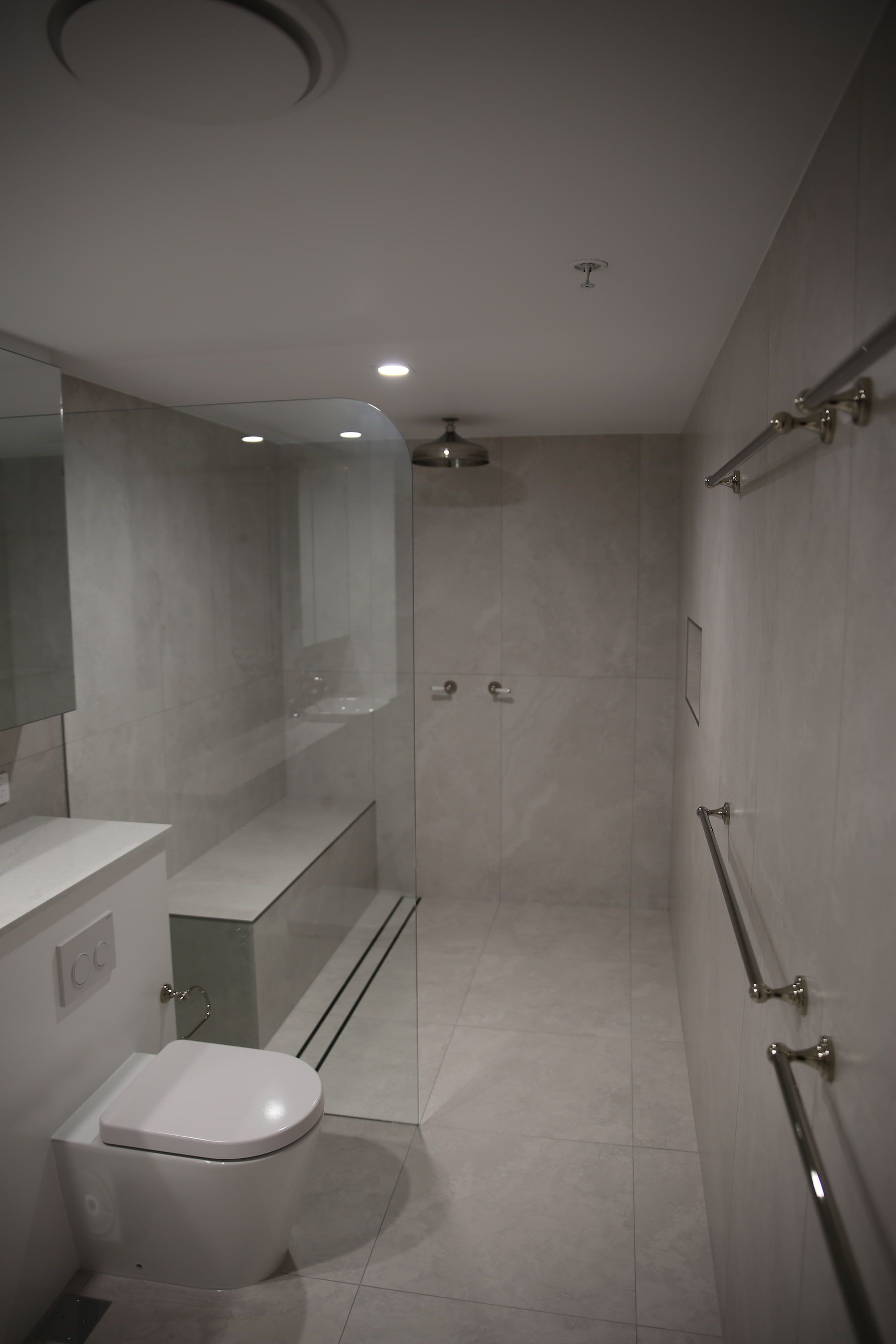 A bathroom with a toilet , shower and mirror.