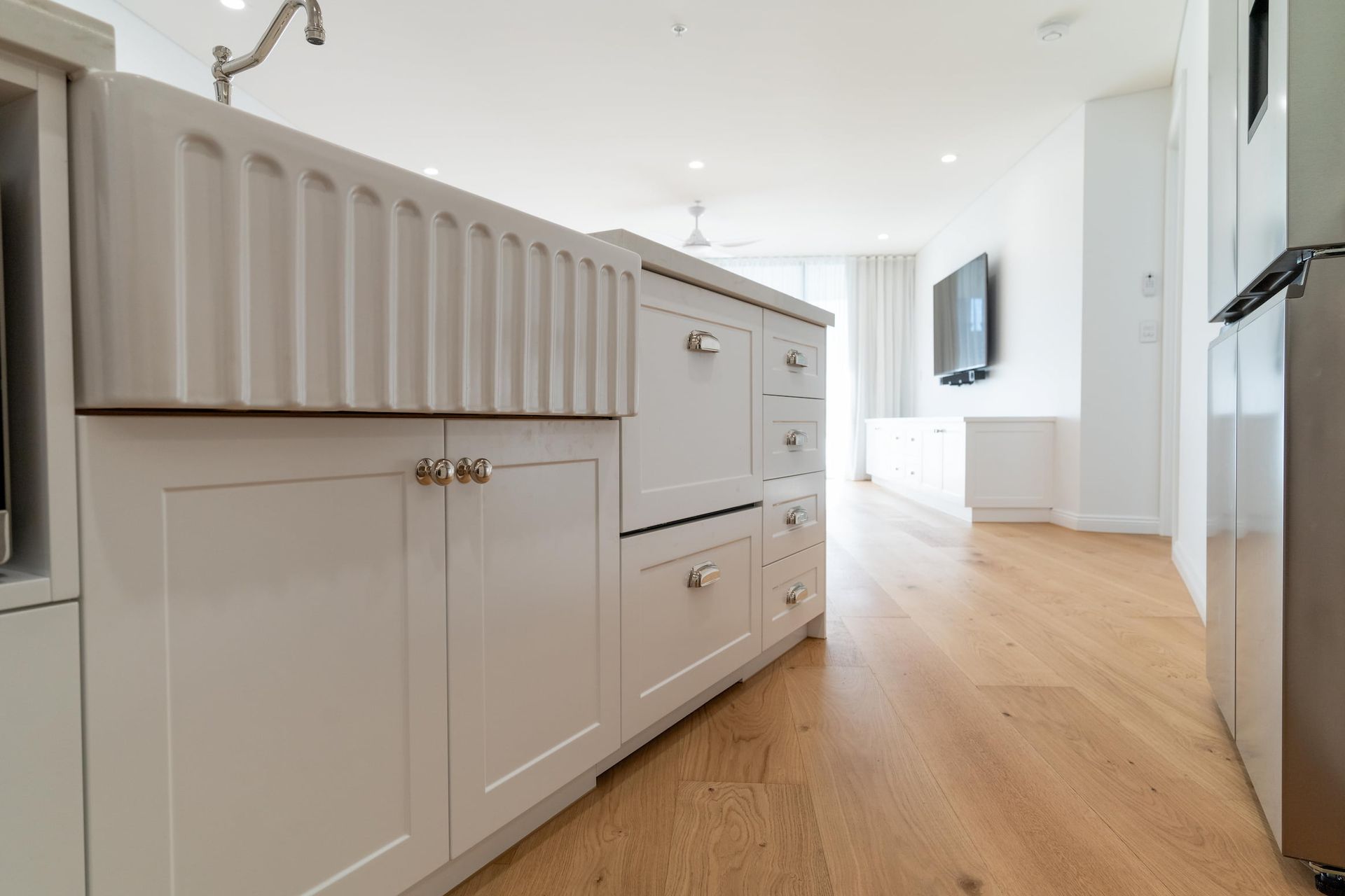 A kitchen with white cabinets , a sink and a refrigerator.