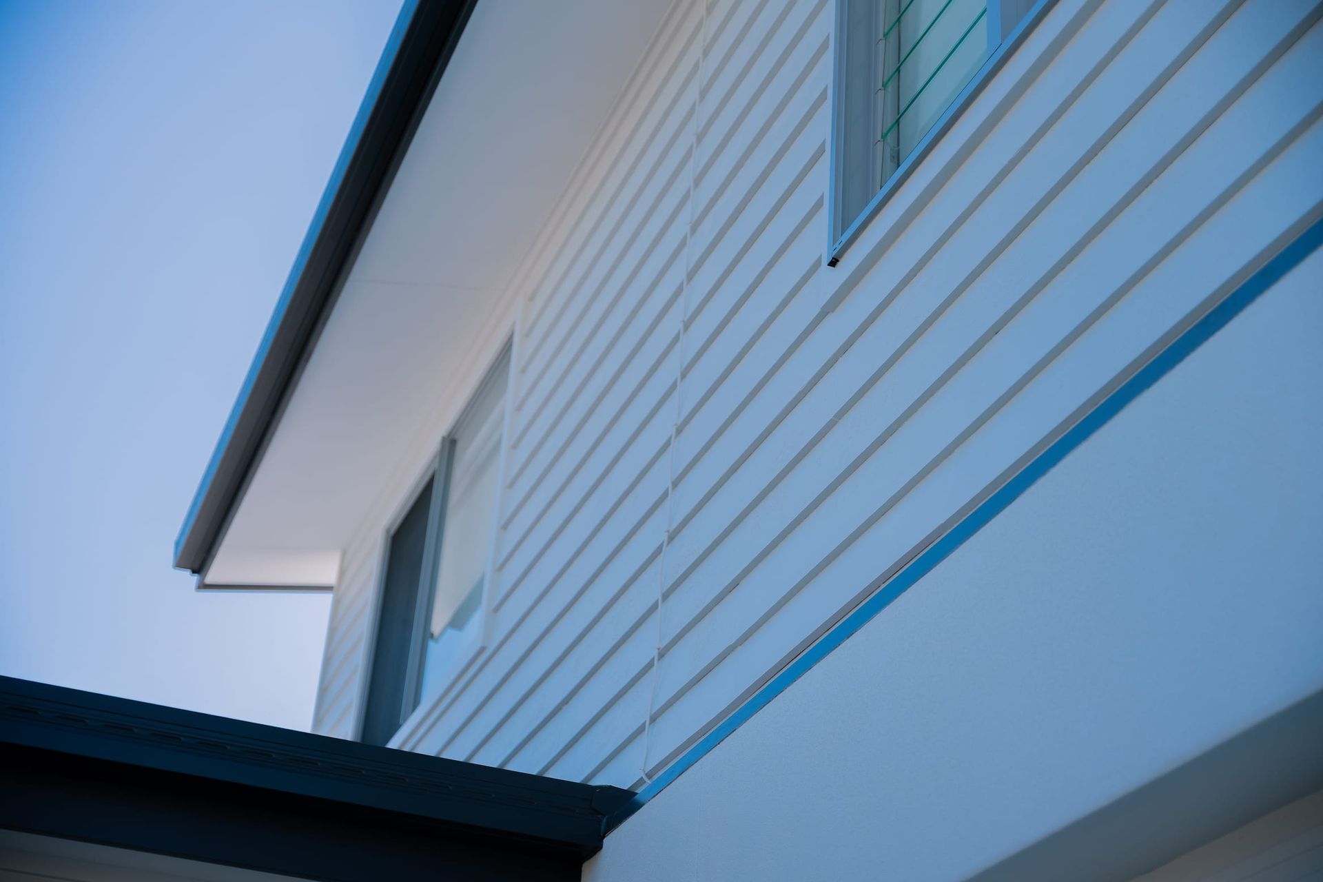 Outdoor seating area with white pergola, beige wicker furniture, and white wooden fence.