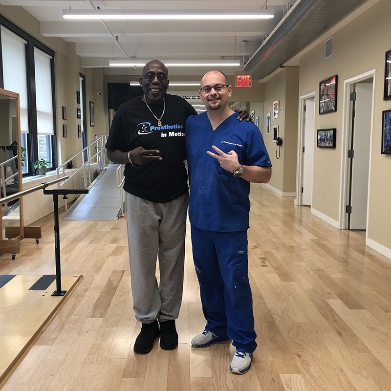 Two men are posing for a picture in a hallway with a red exit sign in the background