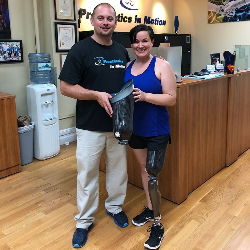 A man and a woman standing in front of a sign that says prosthetics in motion