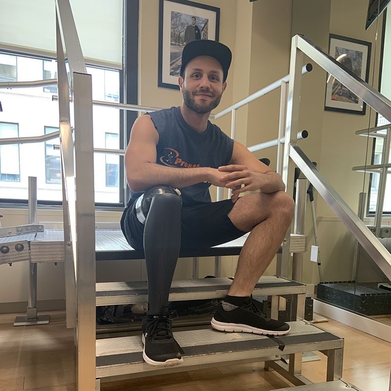 A man with a prosthetic leg is sitting on a set of stairs.