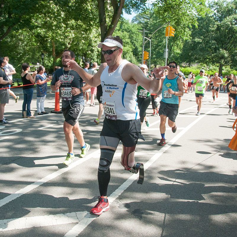 A group of amputees running a marathon and one of them is wearing a shirt that says ' marathon ' on it