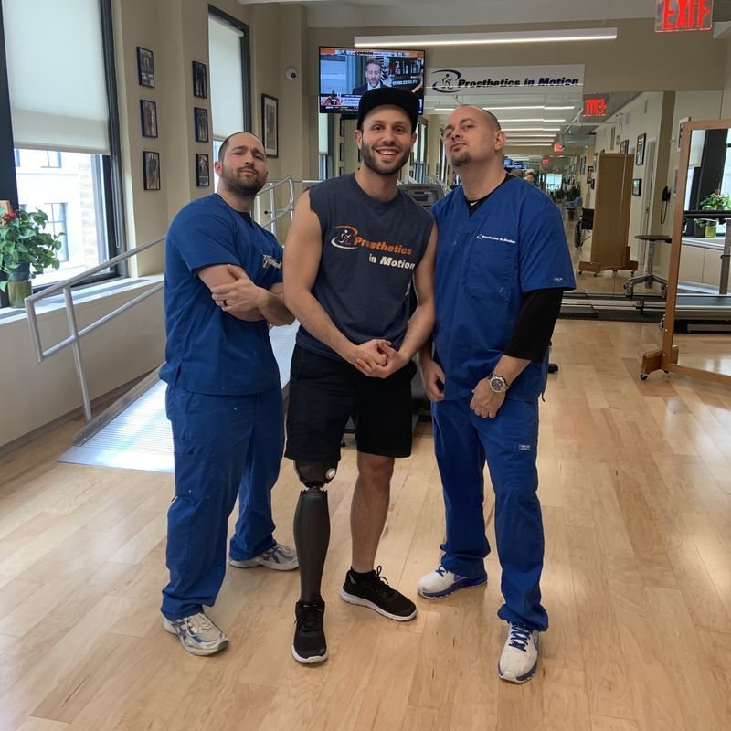 A man with a prosthetic leg poses with two other men