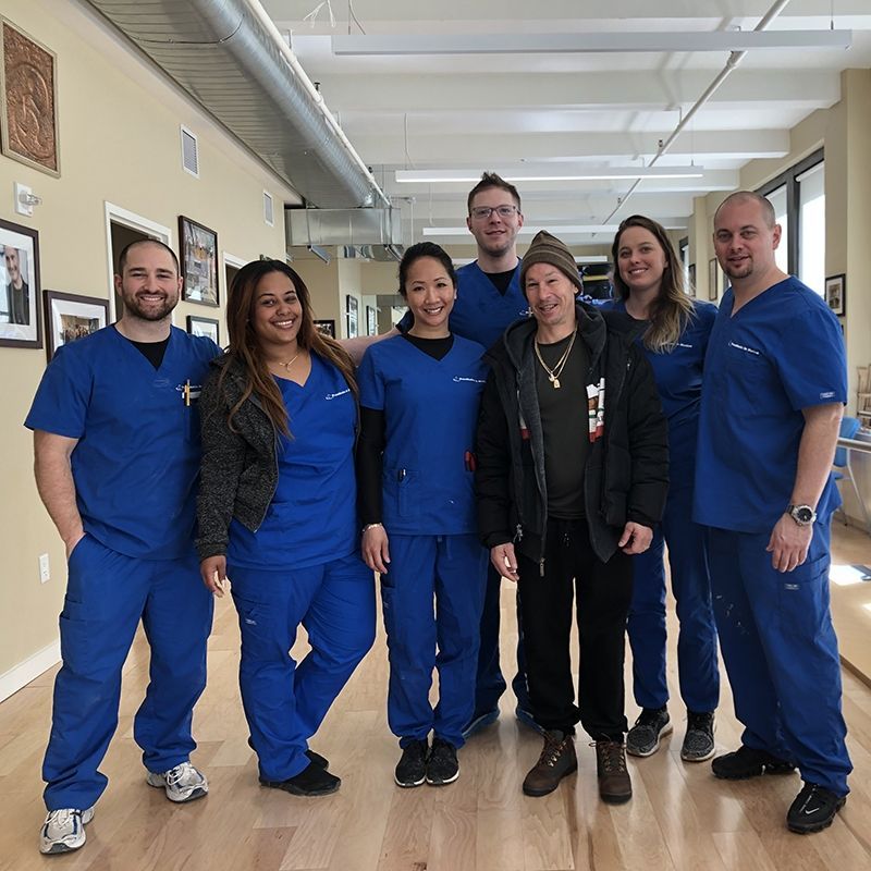 A group of people in blue scrubs pose for a picture