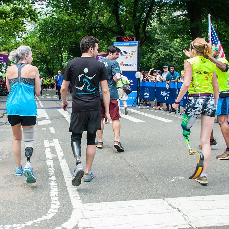 A group of people are walking down a street and one of them has a prosthetic leg