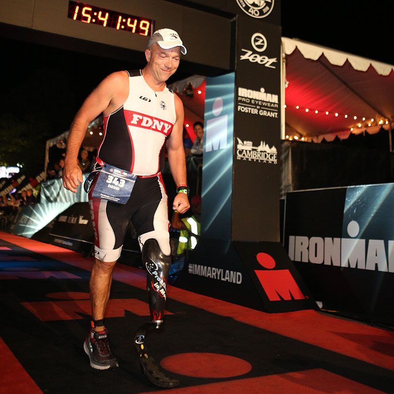 A man with a prosthetic leg walks past a sign that says ironman