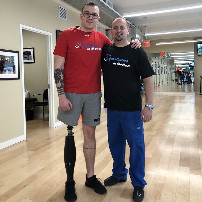A man with a prosthetic leg stands next to another man